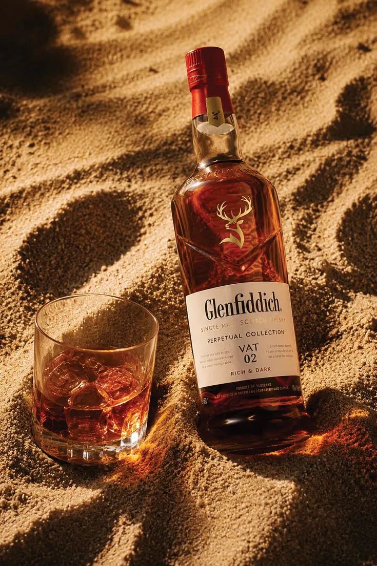 Chai whisky Glenfiddich trên nền cát