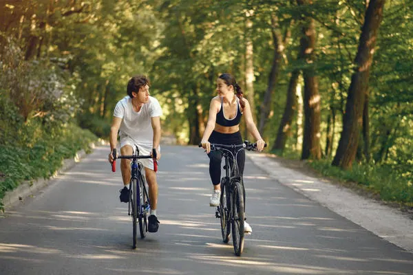Hai người đạp xe giữa con đường xanh
